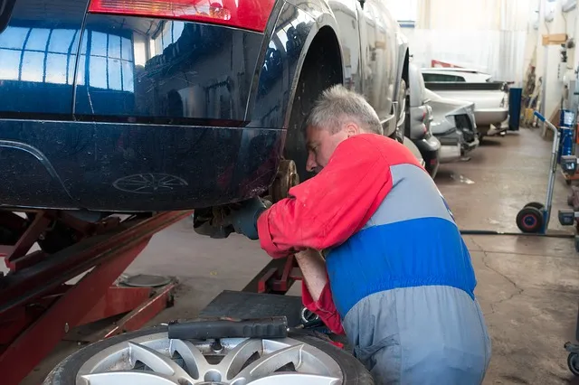 Mechaniker arbeitet unter einem aufgebockten Pkw